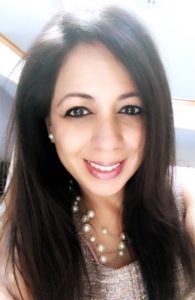 A woman with long, straight dark brown hair smiling at the camera