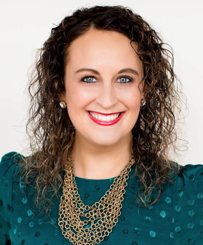 A woman with curly brown hair wearing a green shirt and a gold necklace.