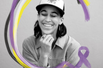 A black and white image of a person smiling with their eyes closed. An illustration of a purple, yellow, white and black ribbon overlays the image.